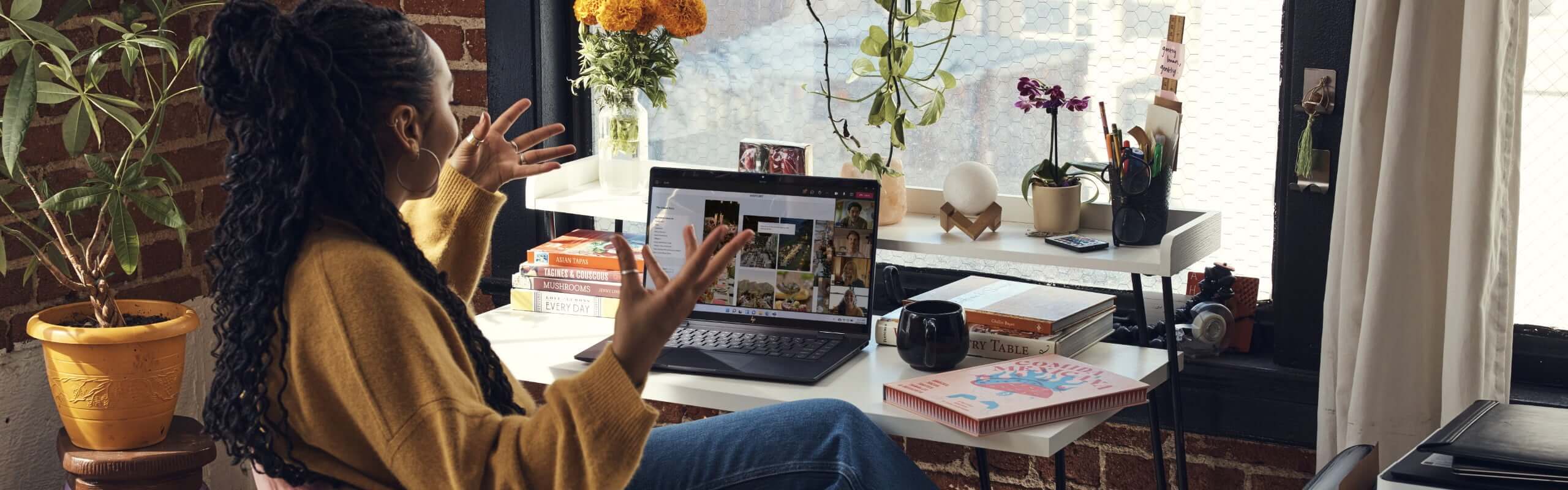 A woman having a virtual conference on her HP Envy laptop in her home office.