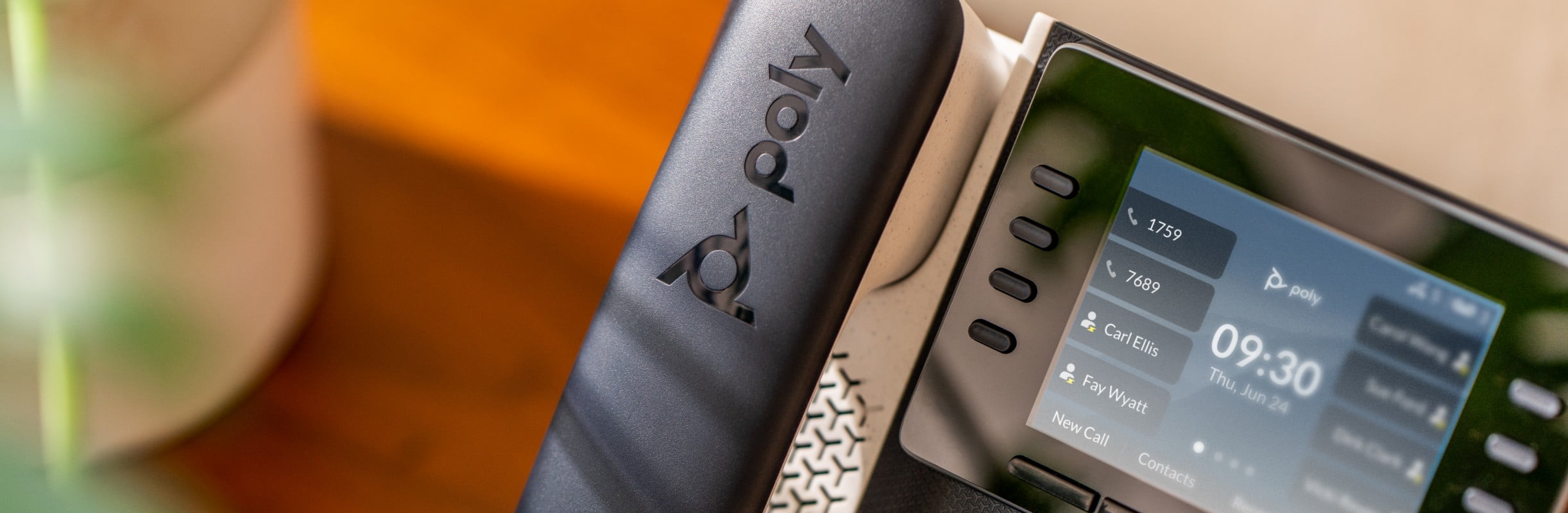 Close up of Poly Edge E350 IP desk phone on a wood credenza, showing multiple lines,menu screen and controls