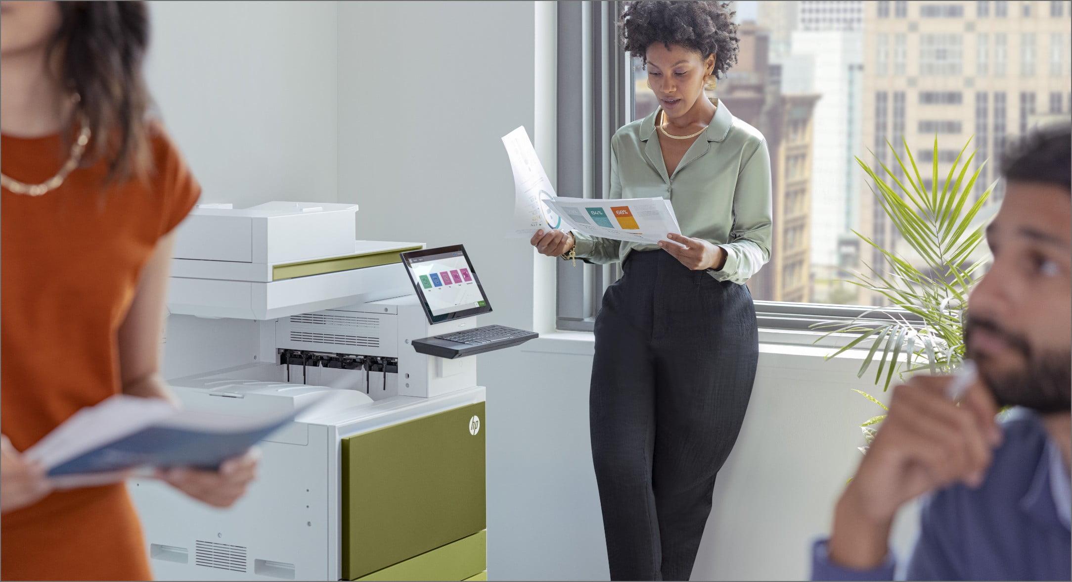 Kvinna som står framför kontorsfönstret och tittar på utskrivna dokument bredvid en HP LaserJet Managed-skrivare