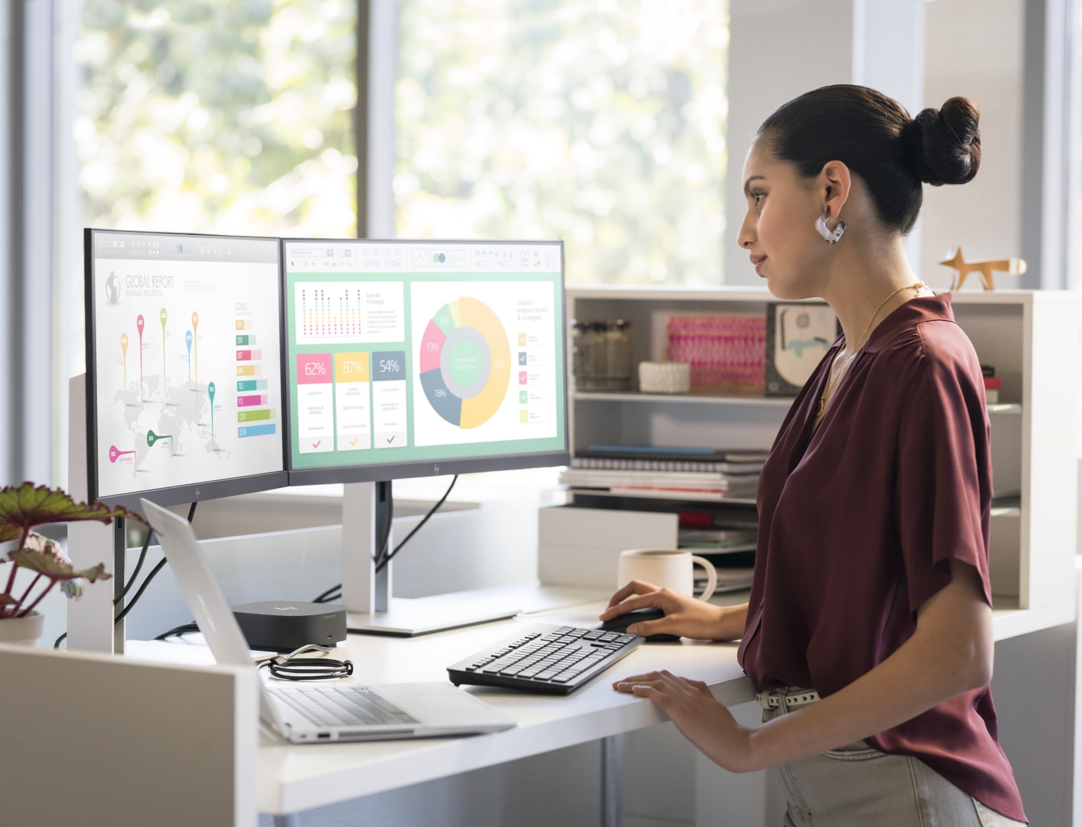 Werknemer die op kantoor bij een bureau staat en naar twee HP monitors kijkt