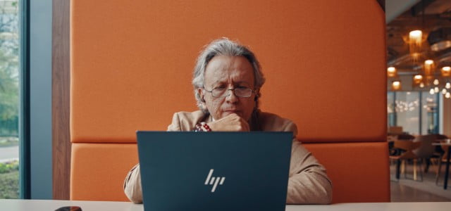 Người đàn ông đang ngẫm nghĩ trong lúc sử dụng máy tính xách tay HP