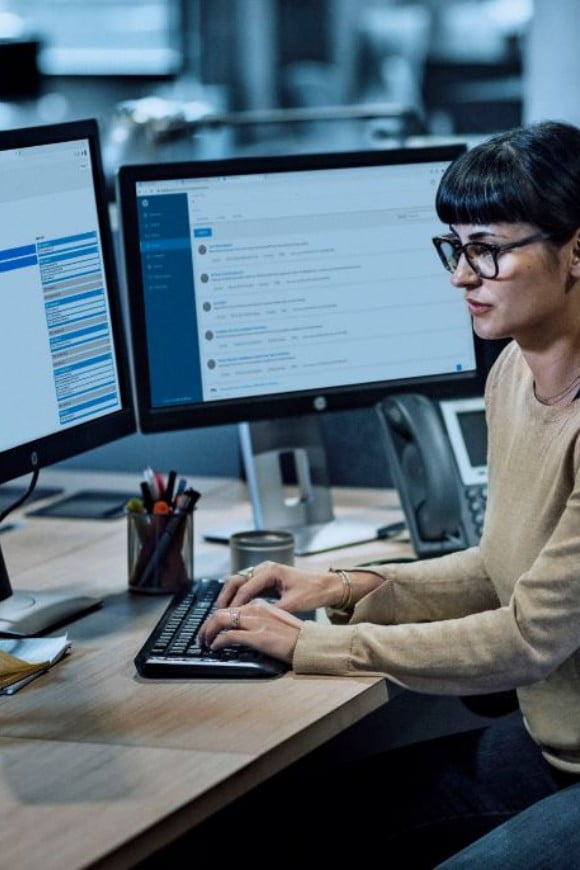 A woman working on dual HP monitors in her office