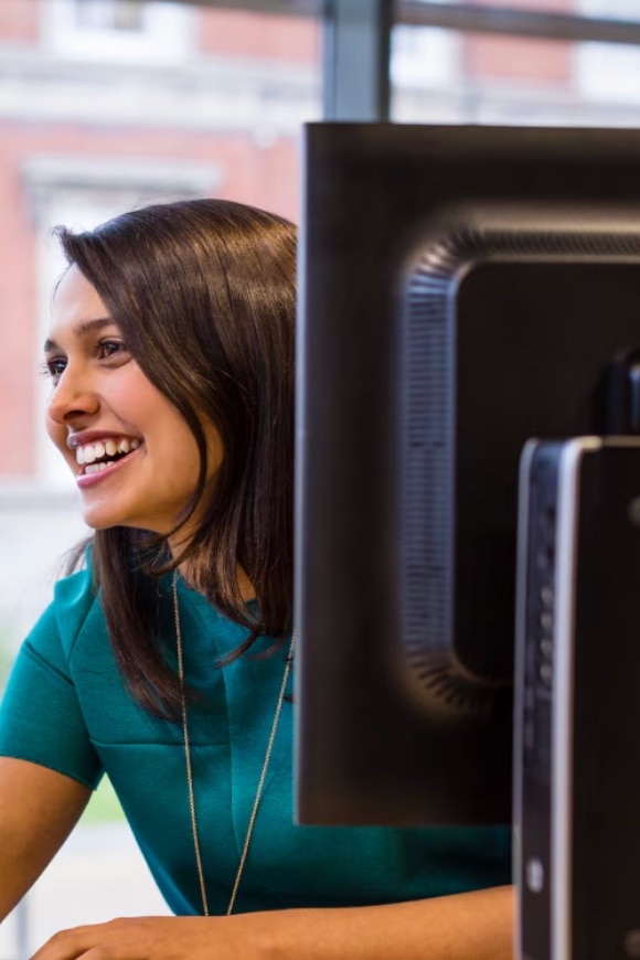 A young woman laughing aside an HP monitor